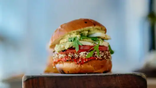 Gourmet quinoa burger from a vegan restaurant in Edmonton, stacked with avocado and fresh veggies.