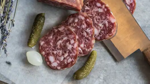 Sliced cured sausage with pickles and pearl onion, showcasing traditional French food in Toronto.