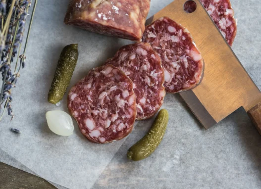 Sliced cured sausage with pickles and pearl onion, showcasing traditional French food in Toronto.