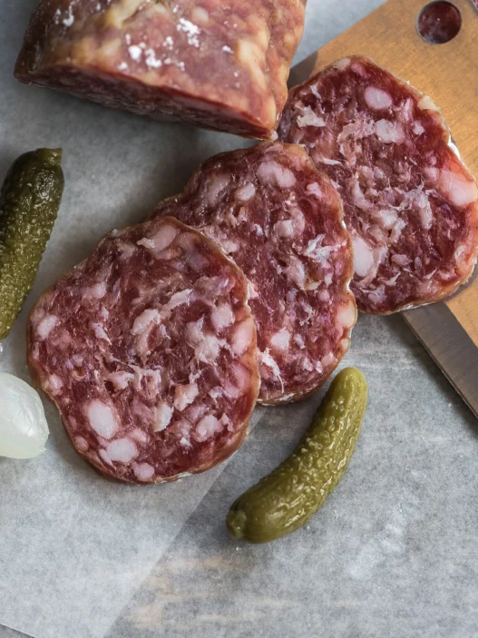 Sliced cured sausage with pickles and pearl onion, showcasing traditional French food in Toronto.
