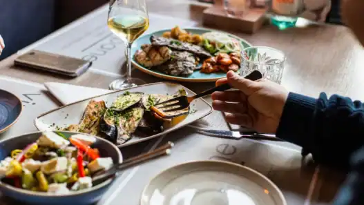 Shared plates of roasted vegetables, grilled meat, and white wine served at a French restaurant in Vancouver.