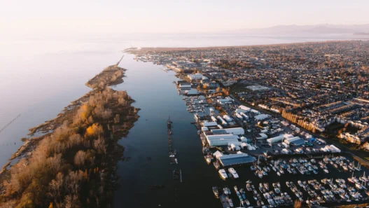 Aerial view of Richmond, British Columbia, with boats, waterfront homes, and peaceful river scenery at sunset.