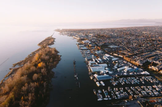 Aerial view of Richmond, British Columbia, with boats, waterfront homes, and peaceful river scenery at sunset.