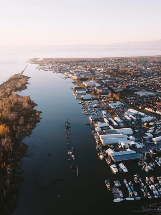 Aerial view of Richmond, British Columbia, with boats, waterfront homes, and peaceful river scenery at sunset.