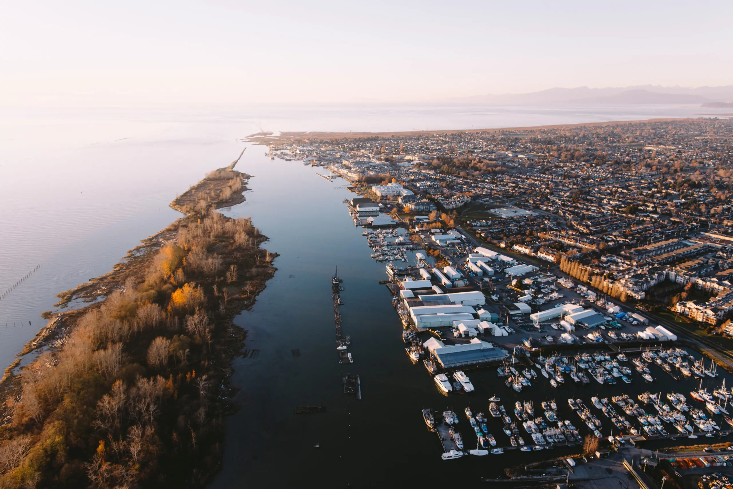 Aerial view of Richmond, British Columbia, with boats, waterfront homes, and peaceful river scenery at sunset.