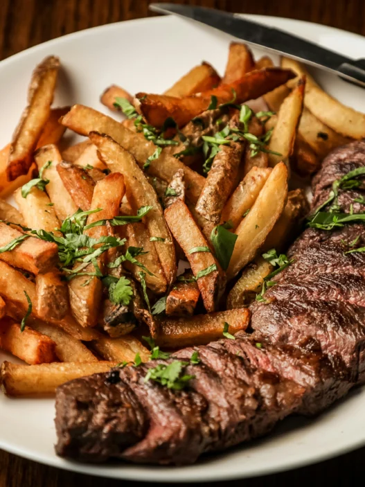 Steak frites at a French restaurant in Montreal with crispy fries and grilled herb-seasoned steak.