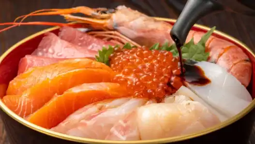 Fresh sashimi bowl at a top Japanese restaurant in Toronto, topped with salmon roe and soy sauce.