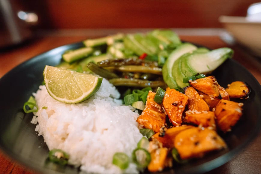 Vegan rice bowl with roasted vegetables and lime, highlighting fresh plant-based cuisine in Vancouver.